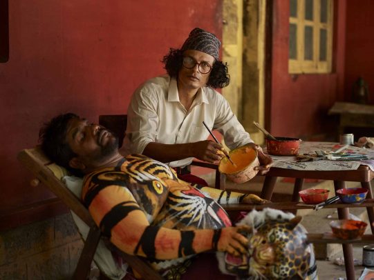 man painting another man with the face of a tiger