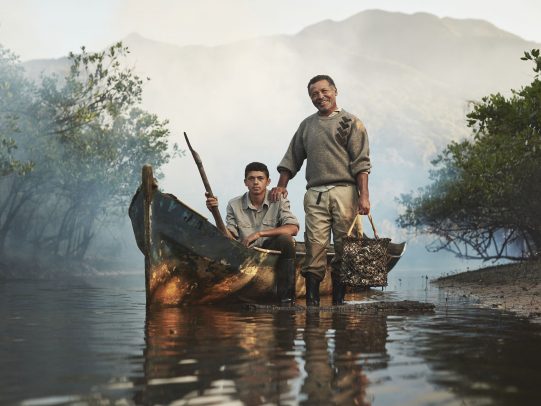 Father and son on a boat in a river for Lavazza Calendar 2016 by Joey L