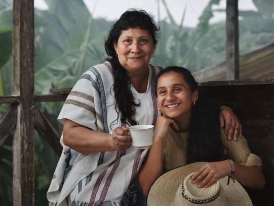 Woman with a cup of coffee hugging a girl who hold a hat for Lavazza Calendar 2016 by Joey L