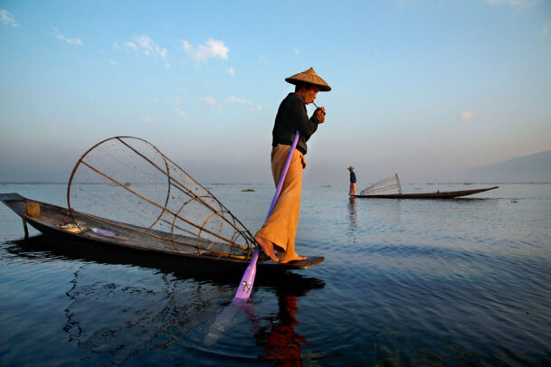 fisherman in Burma lights a cigarette on his boat
