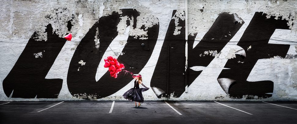 woman dancing holding some baloons in front a big graffiti