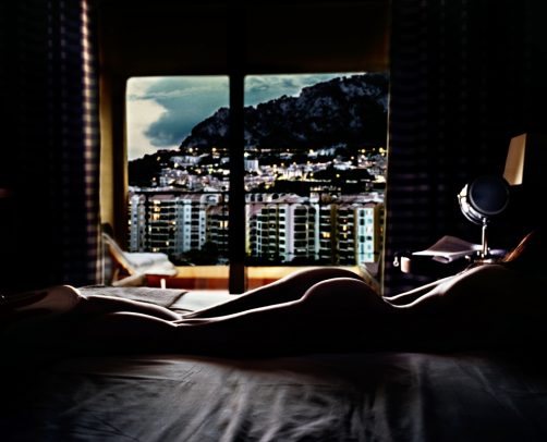 naked woman on the bed and a window with city landscape
