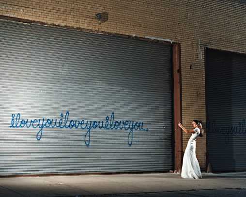 woman with white long dress taking picture of a graffiti on a 