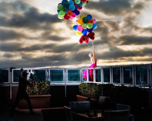 woman in pink dress holding some colorful baloons