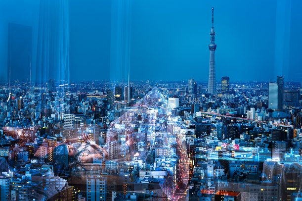 cityscape of Tokyo at dusk with a reflection of a woman on the window