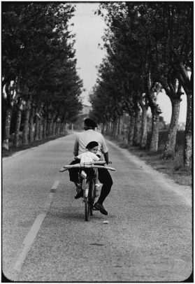 a boy on the bicycle with his grandpa in a tree-line street