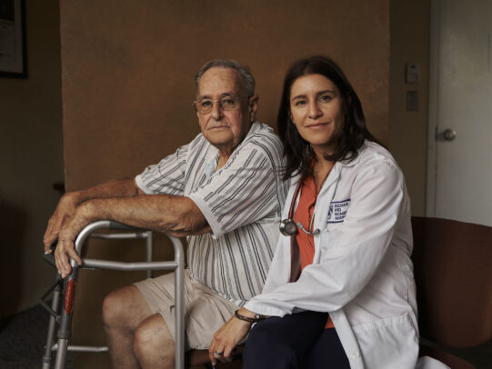 a doctor and her patient with his walker during Novartis annual report by Joey L. 