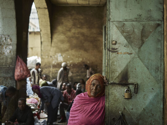 a woman leaning on a door in a market during Novartis annual report by Joey L. 