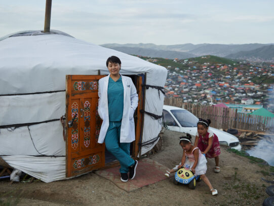 a doctor leaning on the entrance of a yurta during Novartis annual report by Joey L. 