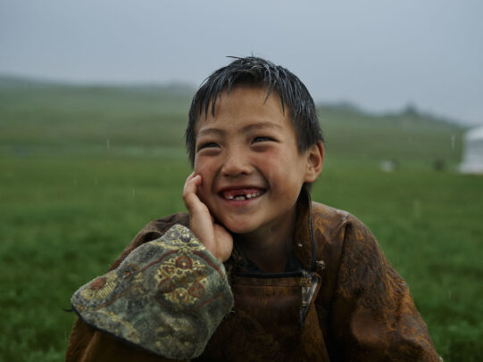 mongolian boy smiling under rain during Novartis annual report by Joey L. 