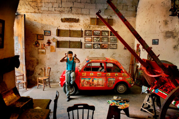 man leaning on a red 500 fiat car in Sicily