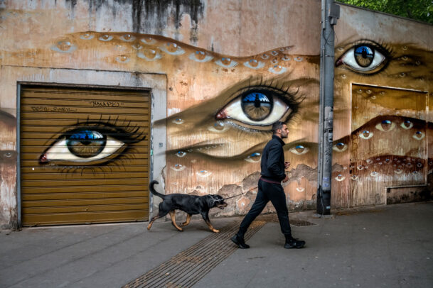 Man with dog passing mural in rome