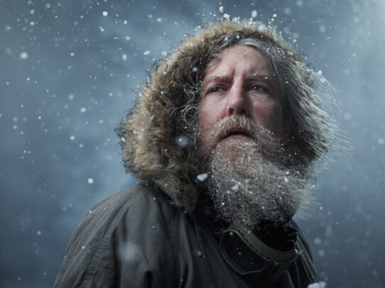 man with beard and hood in a blizzard
