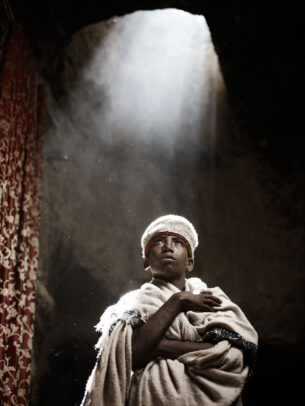 man with white robes and hat under light