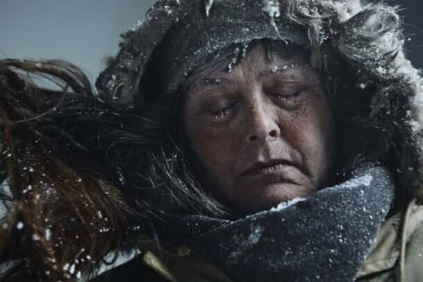 woman with hood and closed eyes in a blizzard