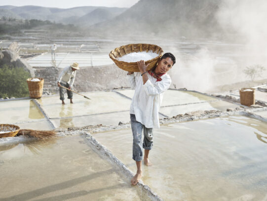 man holding a basket full of salt in a saltwork
