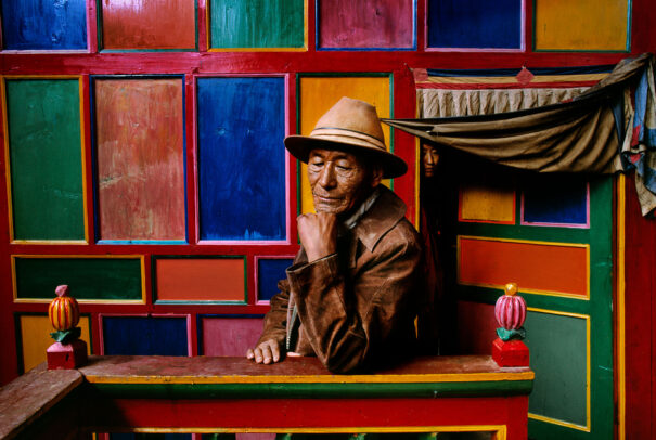 A tibetan man in front of a colorful wall