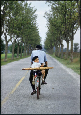 boy on a bicycle with his granfather holding a baguette