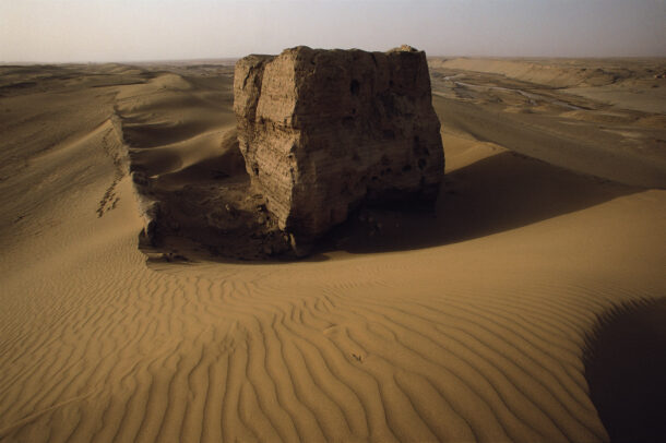 The shell of a Han Wall beacon tower stands in relief against the sand dunes