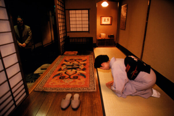 a woman bows to greet guests at a japanese inn