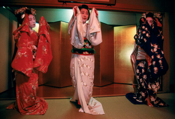 Three geisha in exquisite kimono dance at a party 