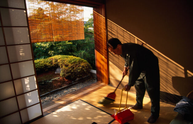 man cleaning a room in a japanese inn with garden outside