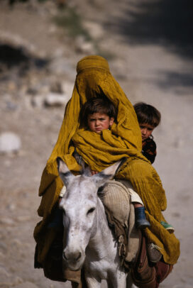 Completely veiled by her burkha, a woman takes her children 