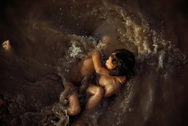 children playing in the murky waters of the Mekong