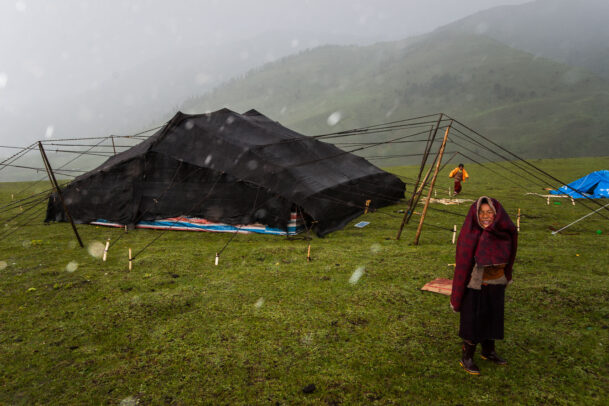 Members of a nomad family weather a sudden storm outside their yak-wool tent