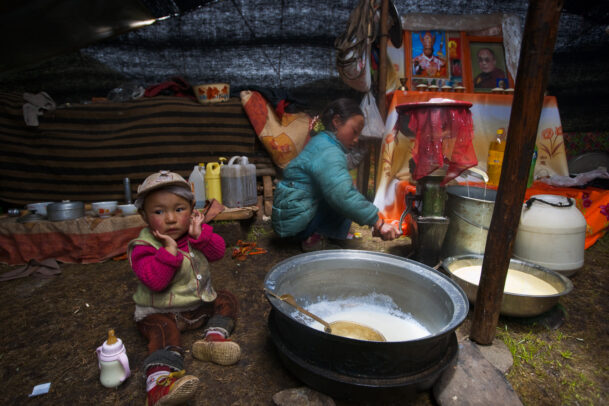 A young boy drinks yak milk near to his elder sister