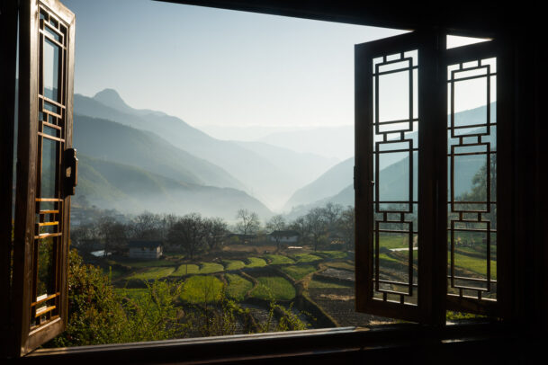 view of the terrace rice fields and misted peaks through a tibetan window