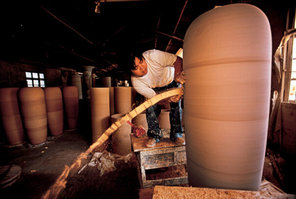 A worker trims a gian pot.