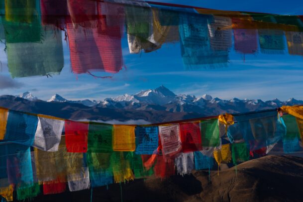 colorful flags in front of the tibetan mountains